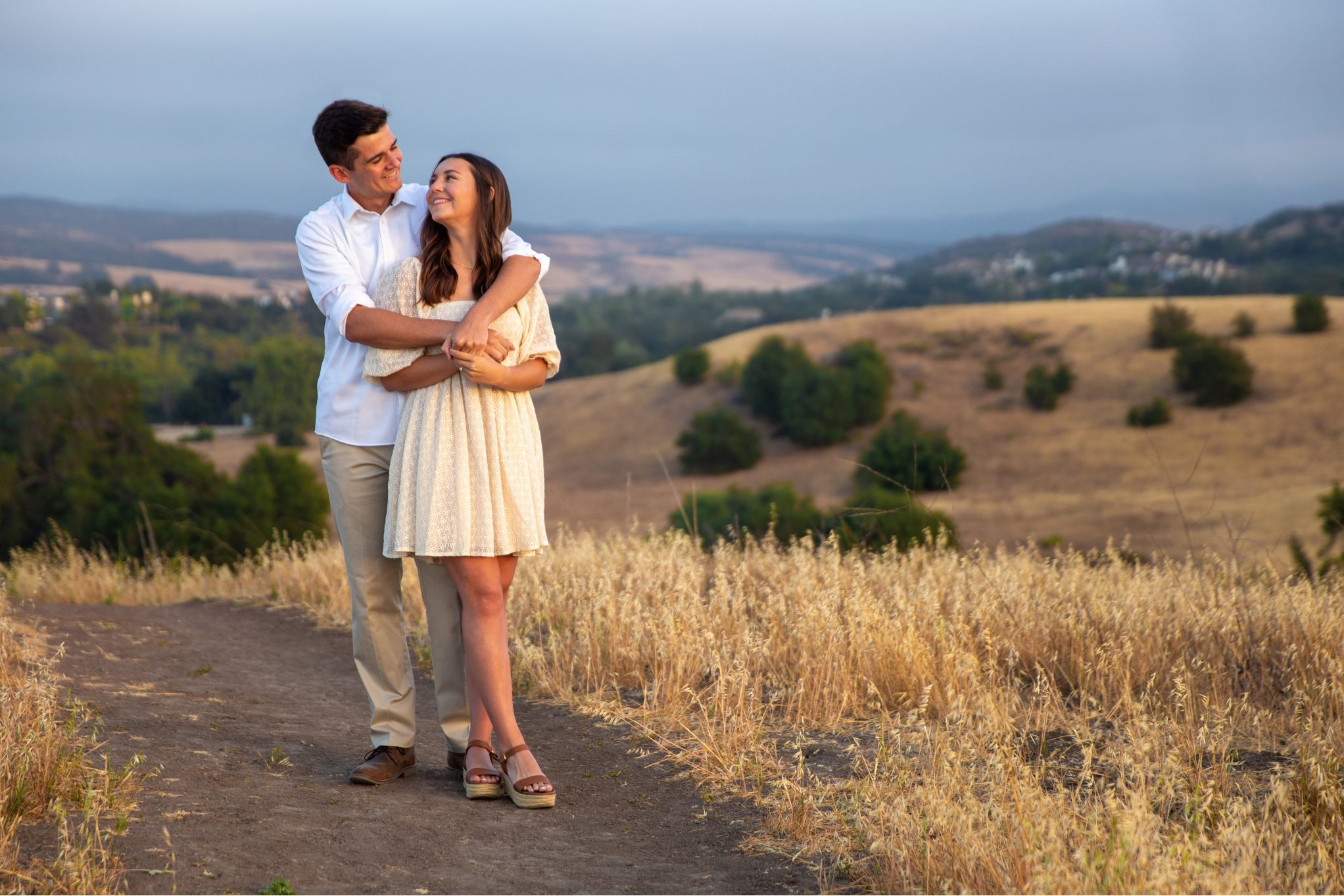 A young couple laughing during an engagement photoshoot in a vibrant Orange County wildflower field.
